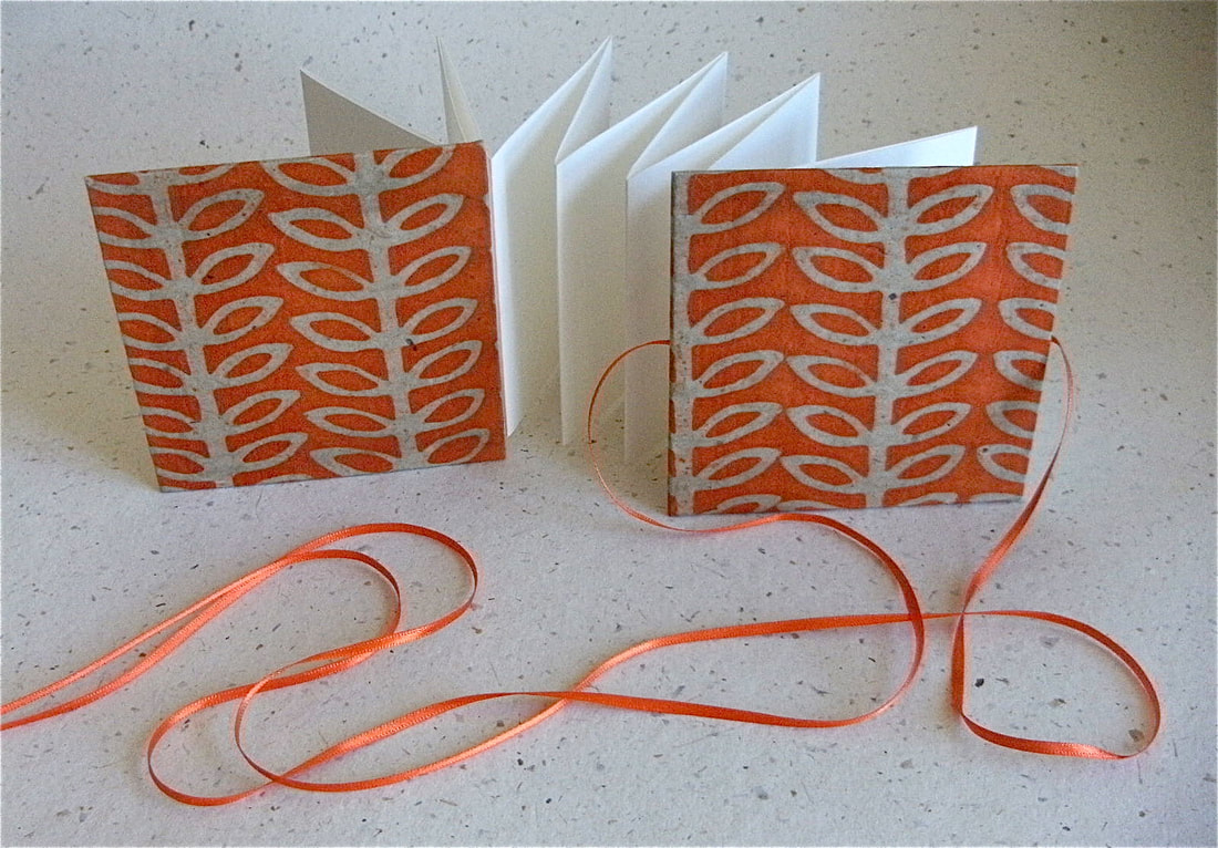 Handmade concertina sketchbook with ornage stem covers, white pages and orange ribbon ties