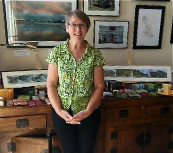 Annie Kerr smiling in front of a display of her artwork and handmade books at Percival Mansions Art House in May 2018